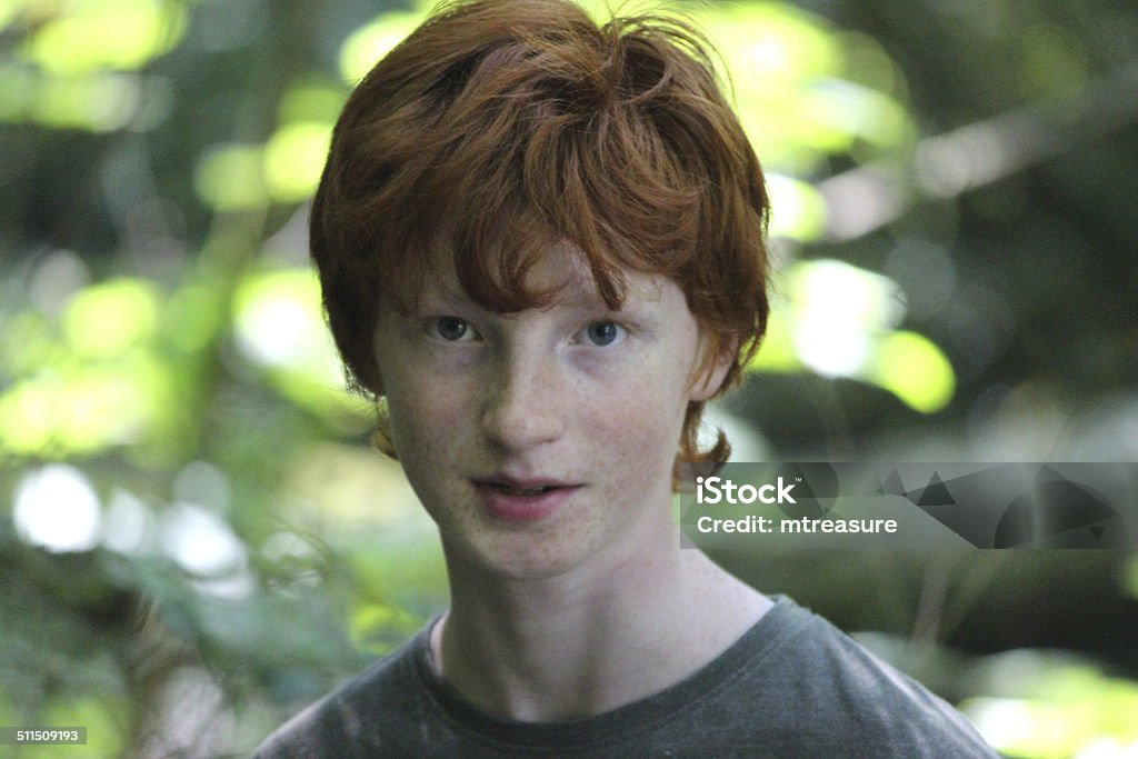 Portrait image of boy, boy's face smiling and laughing, red-hair Photo showing a young teenage boy with short red hair, laughing and smiling to himself as he enjoys a sunny, summer's afternoon walk along a woodland pathway. Adolescence Stock Photo