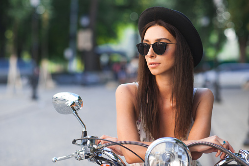 Young woman wearing trendy clothes sitting confident on scooter