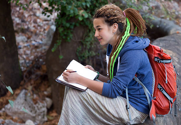 Cute Girl sitting in Forest and drawing sketch note book