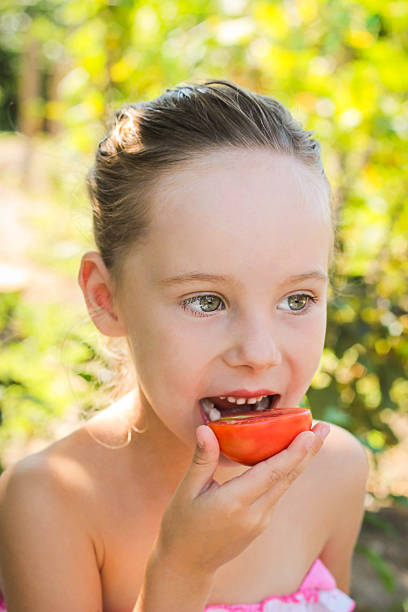 istock beautiful girl eating tomatoes 511524855