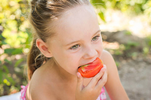 istock beautiful girl eating tomatoes 511524859