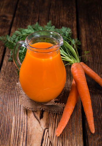 Carrot Juice (selective focus) as close-up shot on wooden background