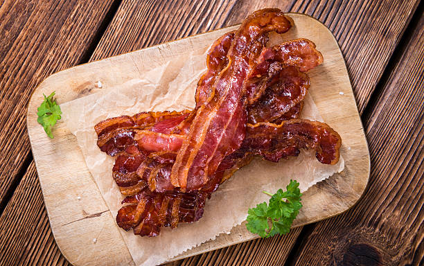 Fried Bacon Fried Bacon (selective focus) on an old vintage wooden table cooked bacon slice stock pictures, royalty-free photos & images