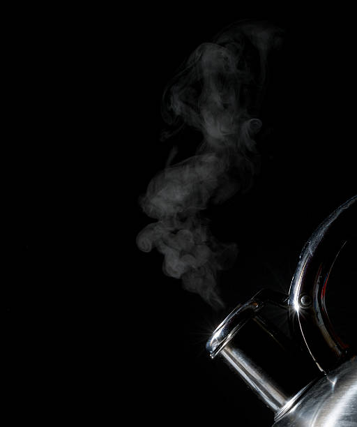 kettle whistling, boiling kettle, steam on a black background stock photo