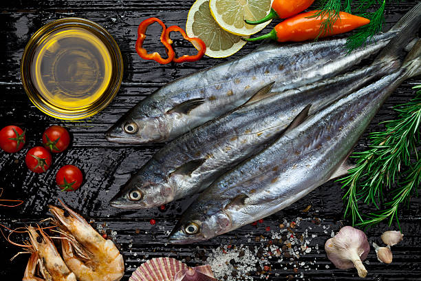 Raw mackerel Three raw mackerel fish shot directly above on dark table with  seafood and  some ingredients for cooking. High angle view DSRL studio photo taken with Canon EOS 5D Mk II and Canon EF 100mm f/2.8L Macro IS USM mackerel stock pictures, royalty-free photos & images