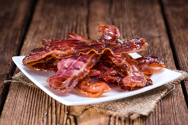 Fried Bacon Fried Bacon (selective focus) on an old vintage wooden table smoked food stock pictures, royalty-free photos & images