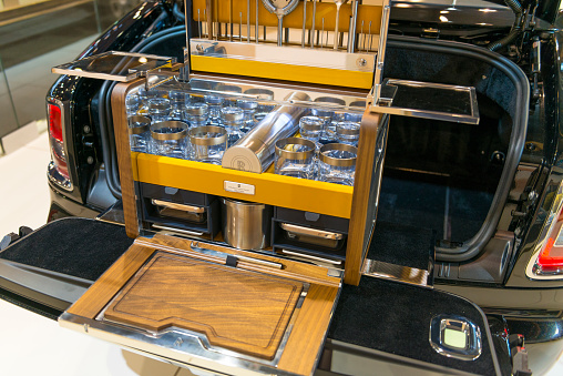 Brussels, Belgium - Januari 12, 2016: Rolls-Royce luxury picnic set in the boot of a Rolls-Royce Phantom Drophead Coupe luxury convertible automobile. The car is on display during the 2016 Brussels Motor Show. The car is displayed on a motor show stand, with lights reflecting off of the body.