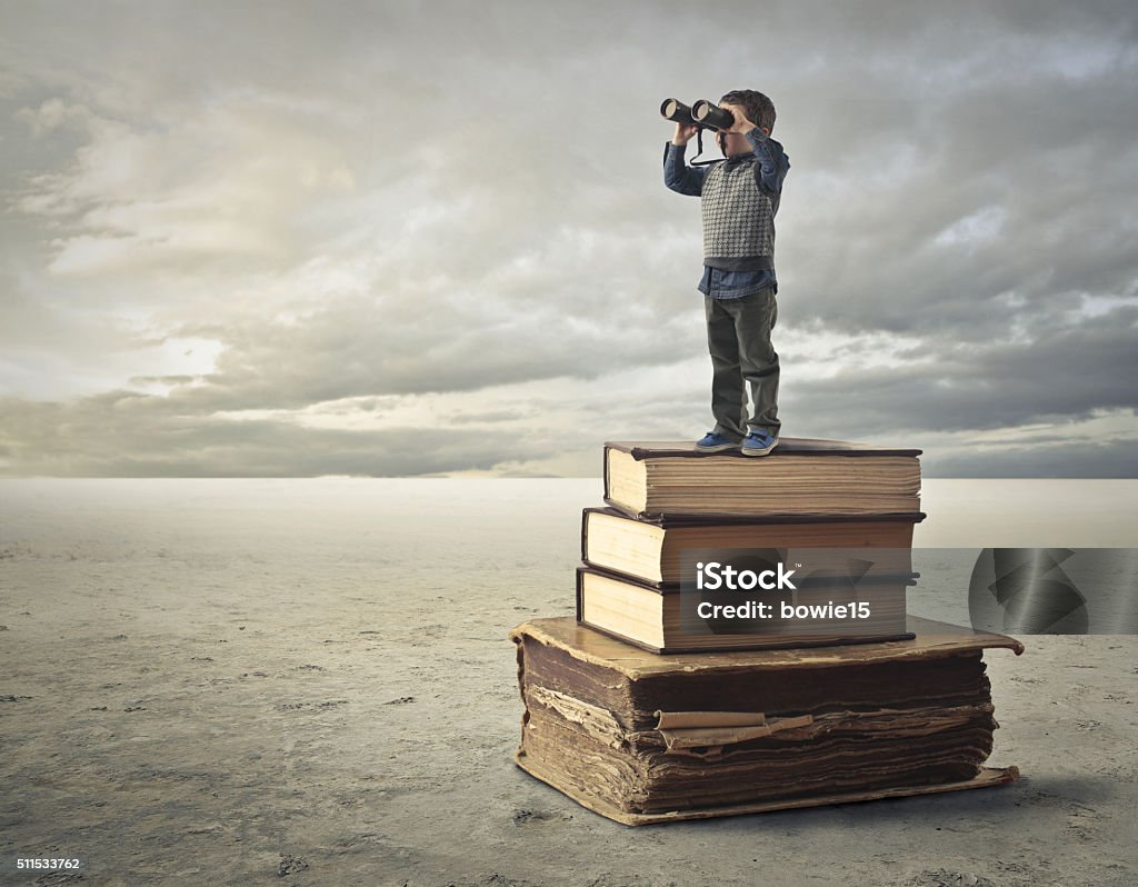 Books of Knowledge A little is illustrated standing on the books which helps him to see further with his binocular Child Stock Photo