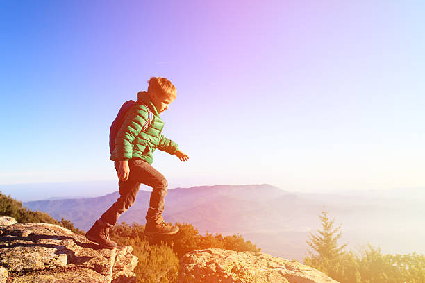 little boy with backpack hiking in scenic mountains