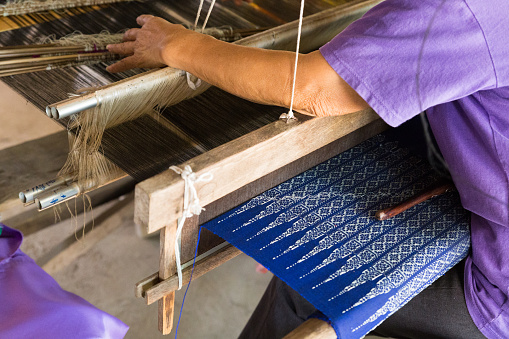 Woman using tradtional loom to weave thailand textile
