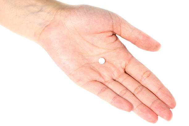 istock white round pills on women hand isolated on white background 511541856