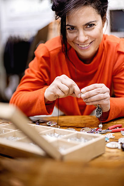 istock Smiling woman making handmade jewelry 511543156