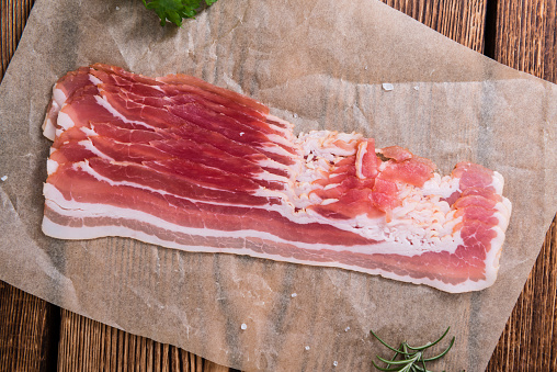 Portion of raw Bacon stripes on wooden background (selective focus)