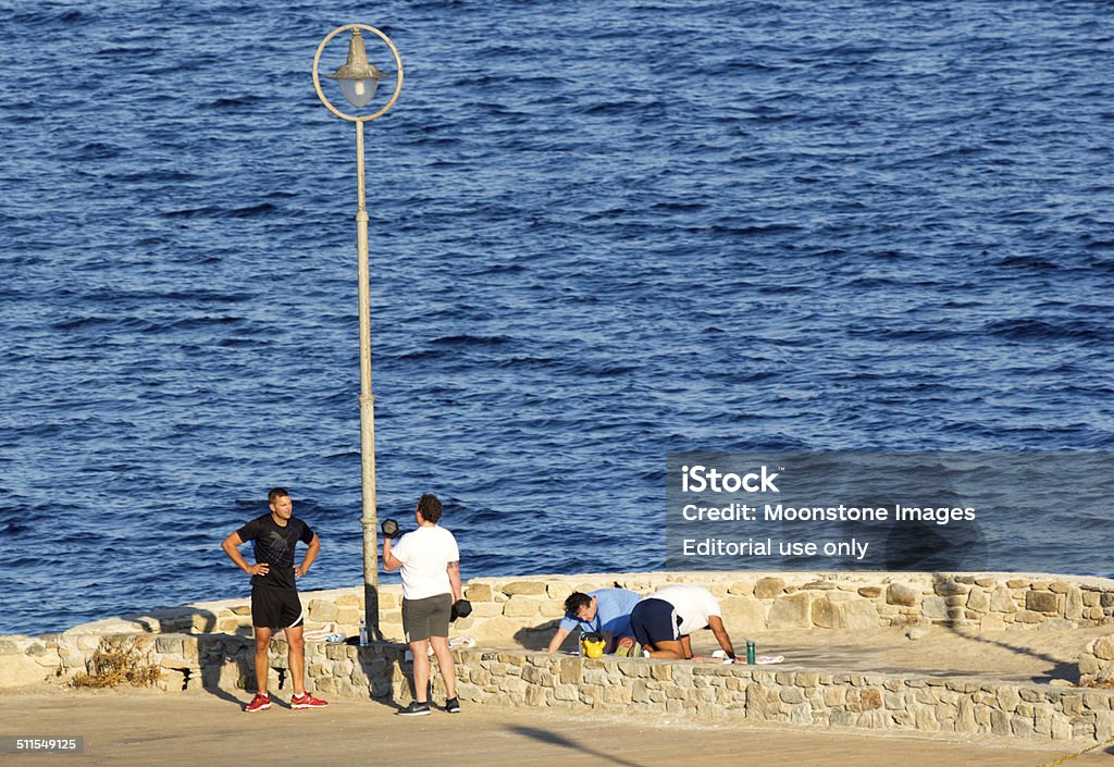 Mykonos Old Port in the Cyclades, Greece Mykonos Town, Greece - September 6, 2014: Four Caucasian men partake in an exercise class in the Mykonos Old Port. Two are doing push ups while another is using barbells for biceps. 30-39 Years Stock Photo