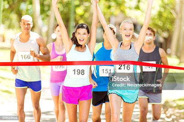 Female Marathon Runners Crossing Finishing Line In Park Stock Photo - Download Image Now