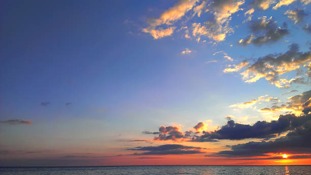 istock Dark yellow-red evening sunset sky with clouds over calm sea 511573017