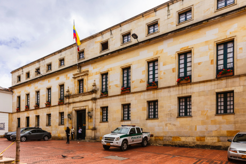 Bogota, Colombia - October 03, 2013: The Ministry of Foreign Affairs in the Palace of San Carlos, located across the road from Teatro Colon. The history of the building goes back to the end of the 16th century when it was built by Archdeacon Francisco Porras Mejia, in 1585. It was used as a Jesuit seminary known as the Colegio Seminario de San Bartolomé. In 1739, the first printing press of Sante Fe was also established here. In 1767, acting on orders from King Carlos III of Spain, it became the Royal Library of Santa Fe and served as barracks for the Presidential Guard. From 1827 to 1908 the palace was the official residence of the President of Colombia. In 1980, the palace was converted to house the Ministry of Foreign Affairs. Some pedestrians walk by the building going about their daily jobs. Photo shot in the afternoon sunlight; horizontal format.
