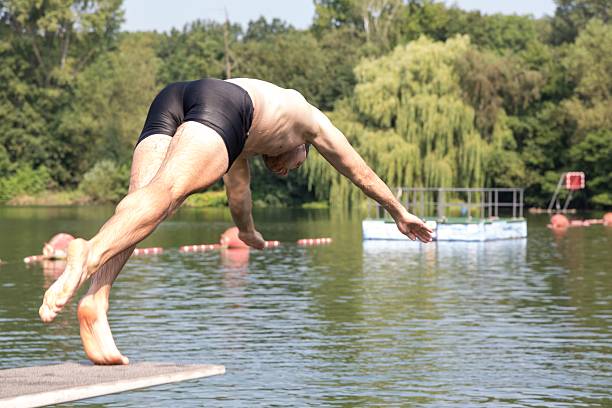 istock Man jumping off diving board at swimming pool 511576717