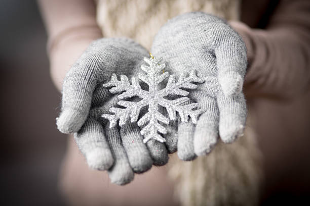 Female hands in mitten with snowflake stock photo