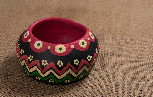 Angled view of a colorful Egyptian handcrafted artistic pottery bowl on a sackcloth background