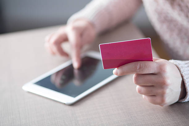 Woman holding credit card while using tablet stock photo