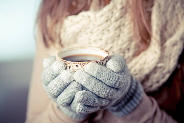 Young woman with mittens holds a coffee cup stock photo