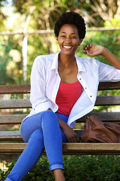 istock Beautiful young african woman sitting on a park bench 511585470