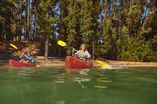 coppia di età matura in canoa su un lago durante un campeggio viaggio - canoeing canoe senior adult couple foto e immagini stock