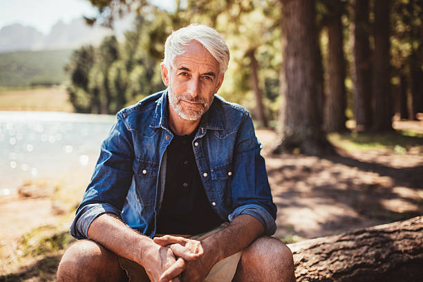 istock Senior caucasian man relaxing on a log by the lake 511586620