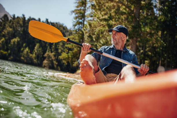 älterer mann kajak paddeln ein - kayak canoeing canoe lake stock-fotos und bilder