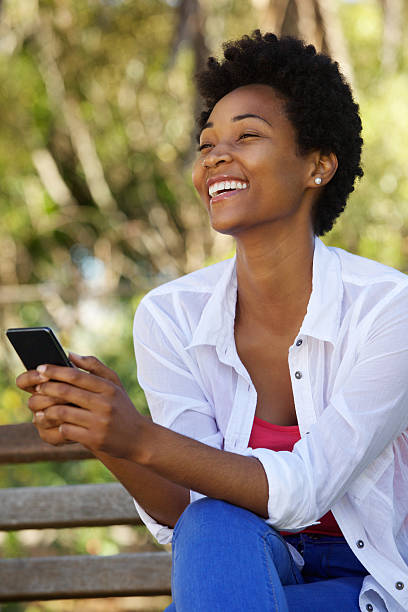 istock Cheerful woman sitting on a bench with a mobile phone 511590582