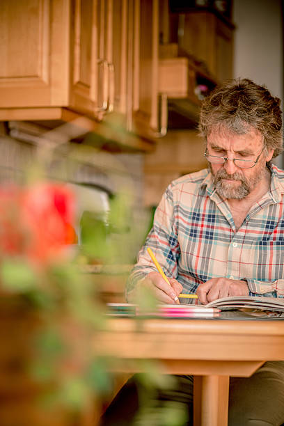 istock Senior Man with Beard Coloring Book at Home,  Europe 511595776