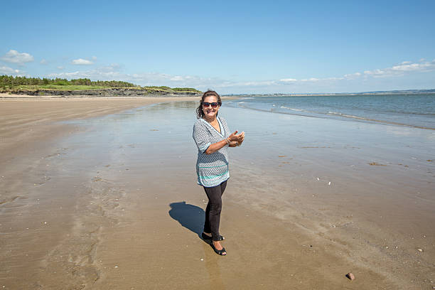 istock Mature smiling woman walking on the beach 511599090
