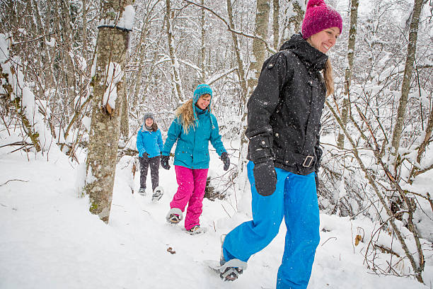 grupo de amigas caminhadas com raqueta de neve na floresta. - snowshoeing winter sport snowshoe hiking - fotografias e filmes do acervo