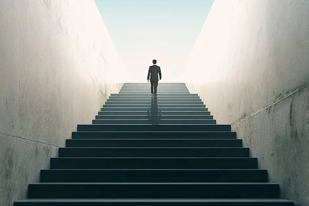 Photo of Ambitions concept with businessman climbing stairs