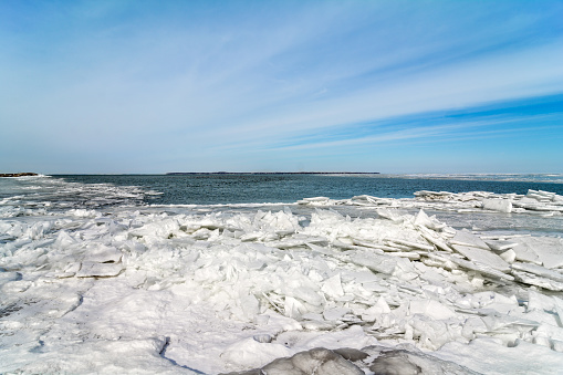 The icy and cold shore of Lake Erie In Northwest Ohio. Large sheets of ice pile up close to thee shore as the wind breaaks the ice up.