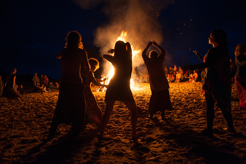 Leningrad Oblast, Russia - July 14, 2015: Big  tourist bonfire on the beach Finland Gulf during the festival. Young people dance and sing around the campfire. Deep night.