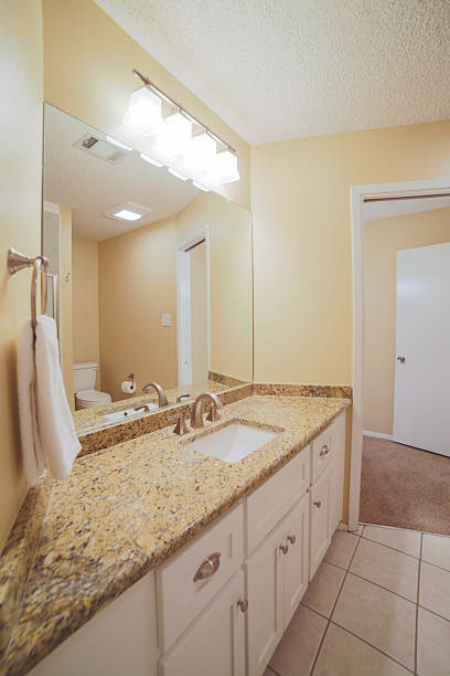 A mirror, a sink with a wooden cabinet, and an open door leading to the toilet in a bathroom