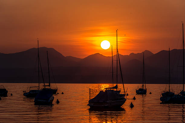 парусные лодки на озере гарда с закате, италия - lake garda sunset blue nautical vessel стоковые фото и изображения