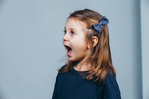 Close up of little cute girl yelling like surprised face on white