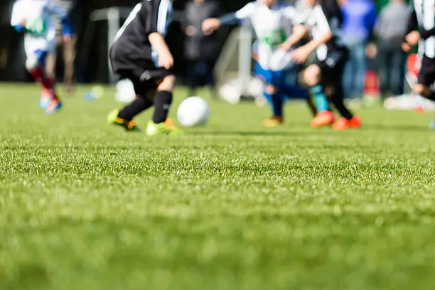 Picture of kids soccer training match with shallow depth of field. Focus on foreground.