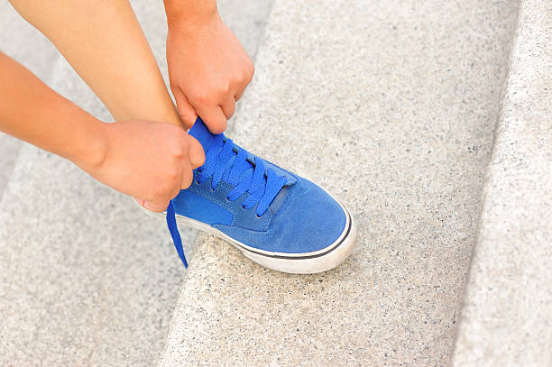 istock woman runner/ skateboarder tying  shoelace 511624277