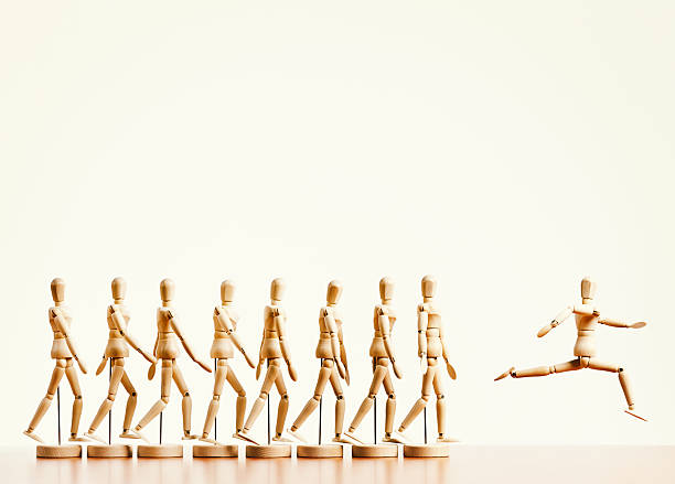 istock Breakaway! Single puppet leaps ahead of marching line. Non-conformist leader! 511644665