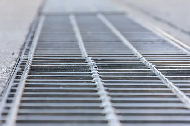 Photo of Black and white close up of a sidewalk subway grate