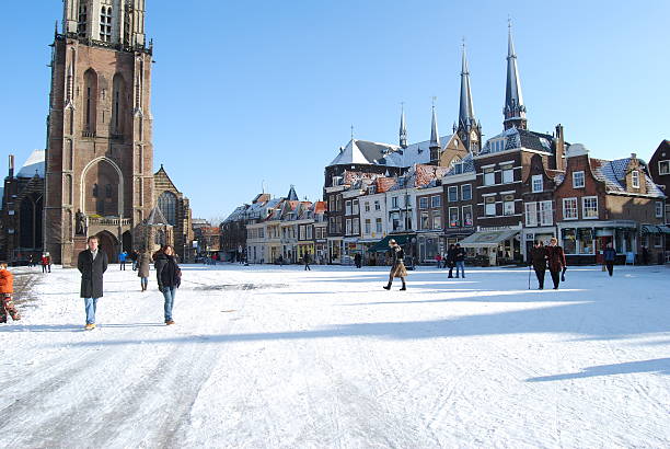 Delft (Netherlands) daily, snowy main square, people blue sky Delft, Netherlands - January 31, 2010: daily and snowy main square of Delft in the Netherlands in the morning with people and blue sky as lifestyle on January 31, 2010 in Delft, Netherlands as editorial delft winter netherlands snow stock pictures, royalty-free photos & images