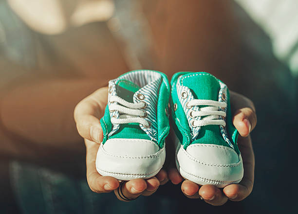 zukünftige eltern mit kleinen schuhen - pair cheerful happiness heterosexual couple stock-fotos und bilder