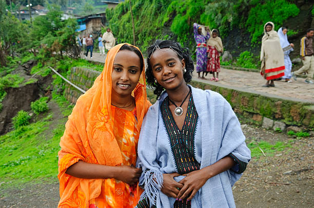 Lalibela, Ethiopia - August 23, 2010: Two sisters stand together in Lalibela, Ethiopia. The orange outfit is native to Harar, Ethiopia. The blue outfit is the traditional style in Lalibela, Ethiopia.