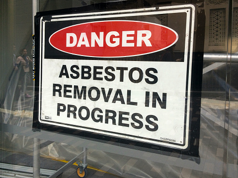 Auckland, New Zealand - October 21, 2015: Sign reads: Danger - Asbestos removal in progress. Inhalation of asbestos fibers can cause serious and fatal illnesses including lung cancer, mesothelioma and asbestosis.