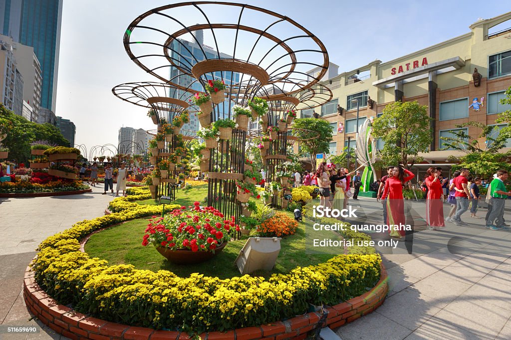 Nguyen Hue street walk in the Lunar New Year Hochiminh City, Vietnam - February 07, 2016: Nguyen Hue walking street with icons of green chung cake, watermelon, yellow apricot flowers. It created warm atmosphere to evryone welcoming the New Year in downtown HoChiMinh. Adult Stock Photo