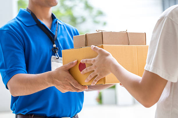 donna mano accettare una linea di scatole da deliveryman - corriere foto e immagini stock